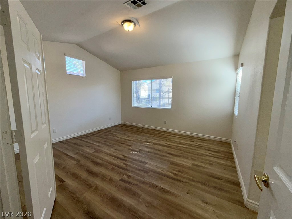 9729 Trail Rider Drive Las Vegas, NV 89117 - Photo 13 of 26 Natural light fills this bedroom featuring attractive hardwood flooring and a vaulted ceiling.