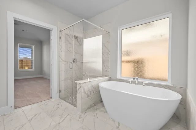 a white bath tub sitting in a bathroom next to a window