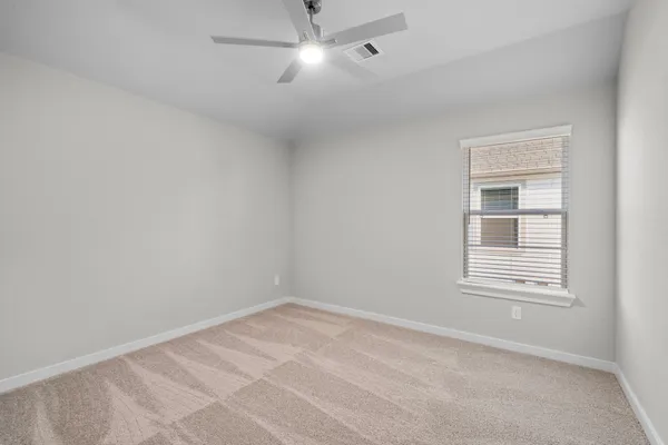 an empty room with a window and ceiling fan