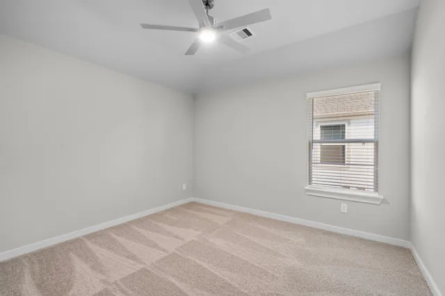 an empty room with a window and ceiling fan