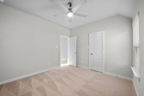 a view of an empty room and a ceiling fan and window