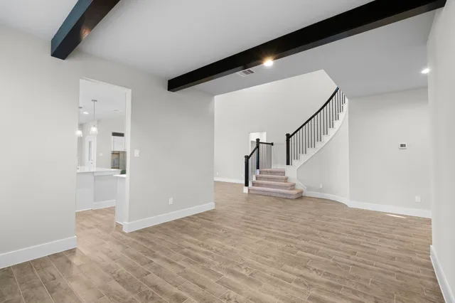 a view of an empty room with wooden floor and stairs