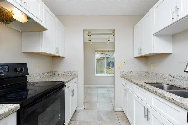 a kitchen with granite countertop a sink a stove and cabinets