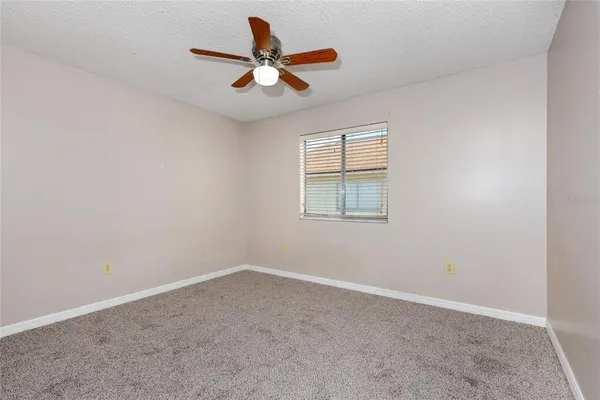 an empty room with a window and a fan