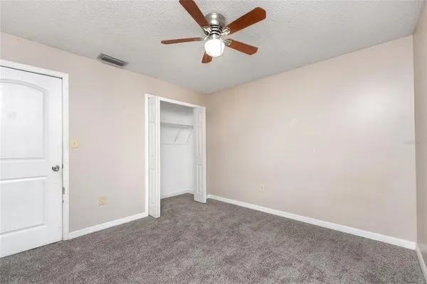 an empty room with closet and a ceiling fan