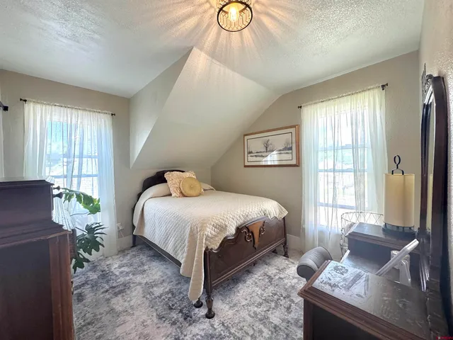 a spacious bedroom with a bed and wooden floor