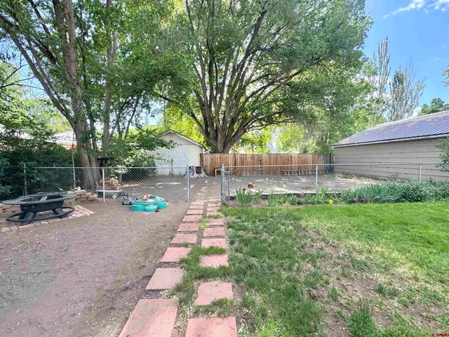 a view of a backyard with table and chairs and a large tree