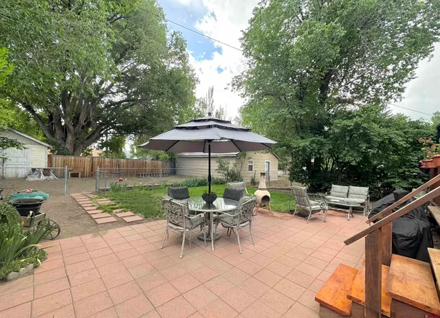 a view of a patio with a table and chairs under an umbrella
