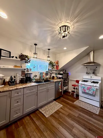 a kitchen with stainless steel appliances granite countertop a sink dishwasher stove and cabinets with wooden floor