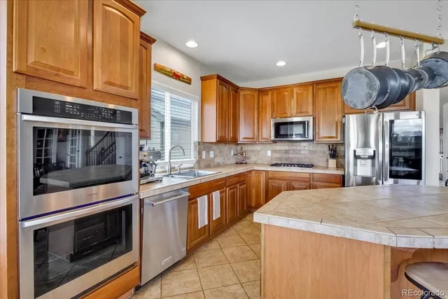 a kitchen with stainless steel appliances granite countertop wooden cabinets a stove and a sink