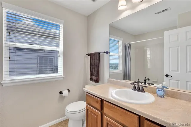 a bathroom with a granite countertop sink toilet and mirror