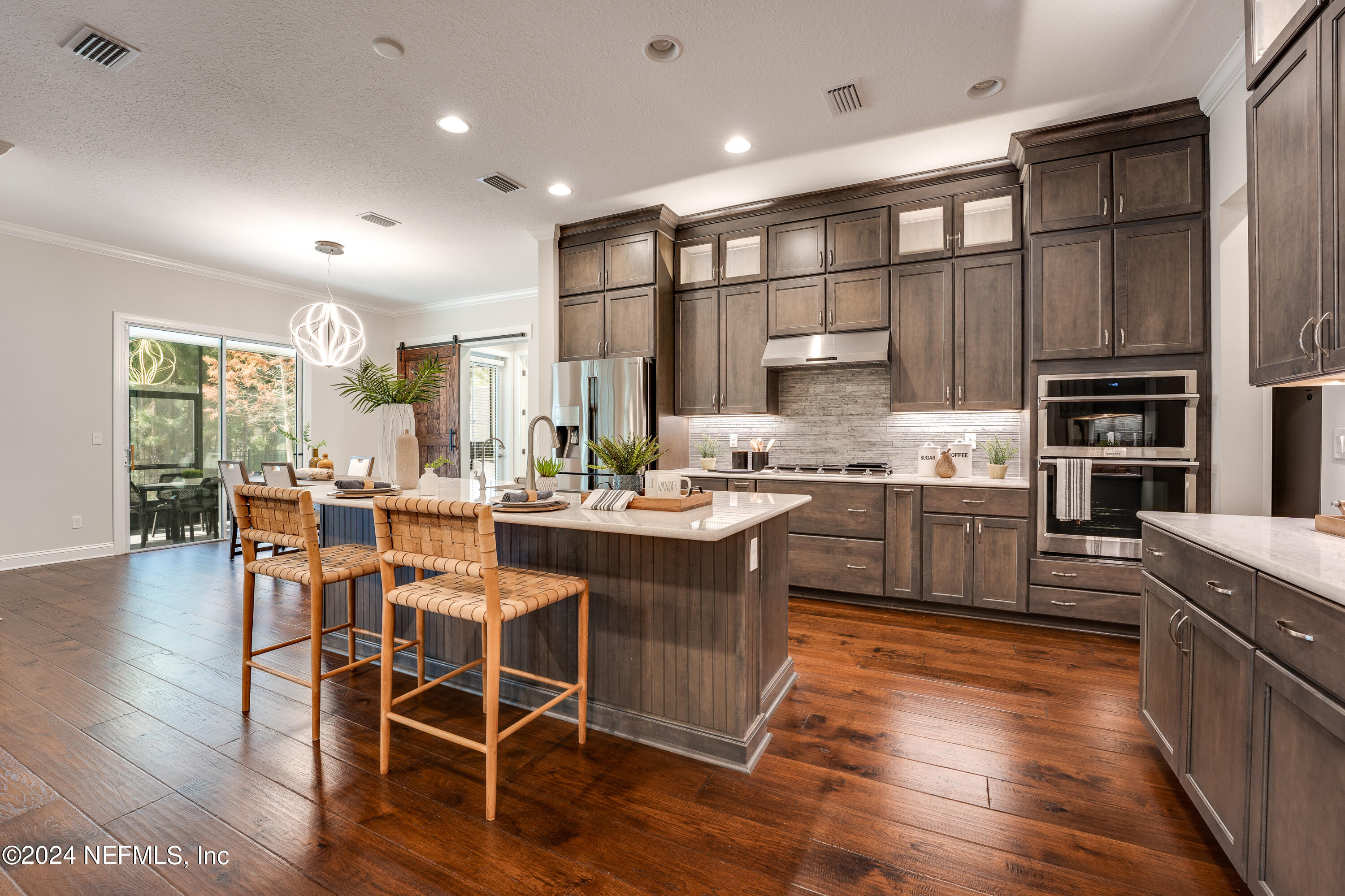 257 Glenneyre Circle St. Augustine, FL 32092 - Photo 14 of 98 a kitchen with stainless steel appliances kitchen island granite countertop a stove a refrigerator a sink a dining table and chairs with wooden floor