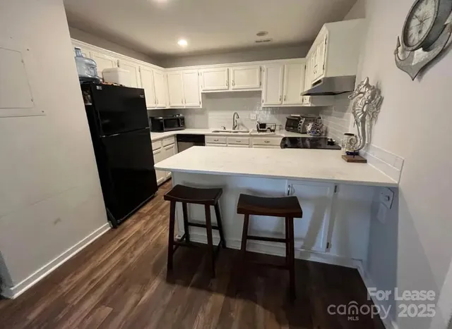 a kitchen with stainless steel appliances a refrigerator a stove a sink and a stove with wooden floor