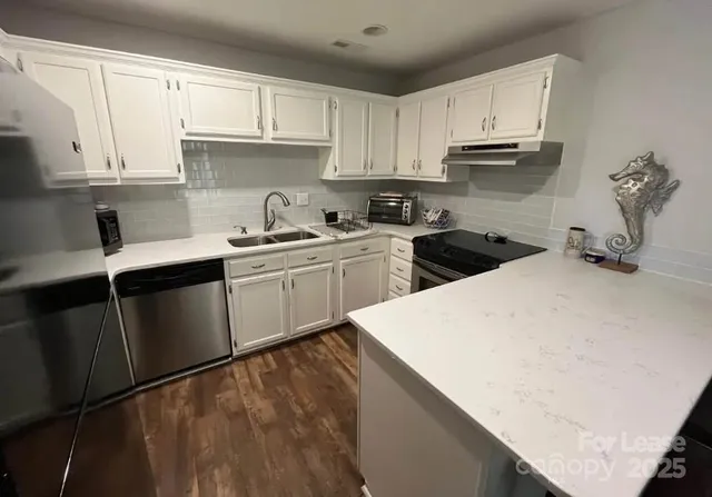 a kitchen with stainless steel appliances granite countertop a sink a stove and white cabinets