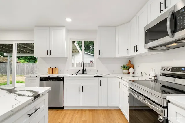 a kitchen with a sink white cabinets and appliances
