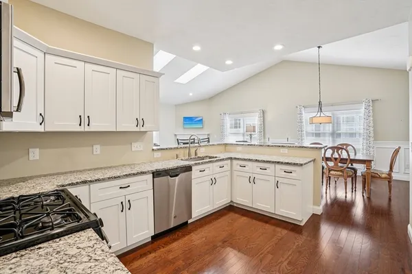 a kitchen with stainless steel appliances granite countertop a stove a sink dishwasher and a refrigerator with wooden floor