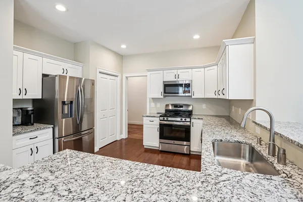 a kitchen with stainless steel appliances granite countertop a refrigerator sink stove microwave and cabinets