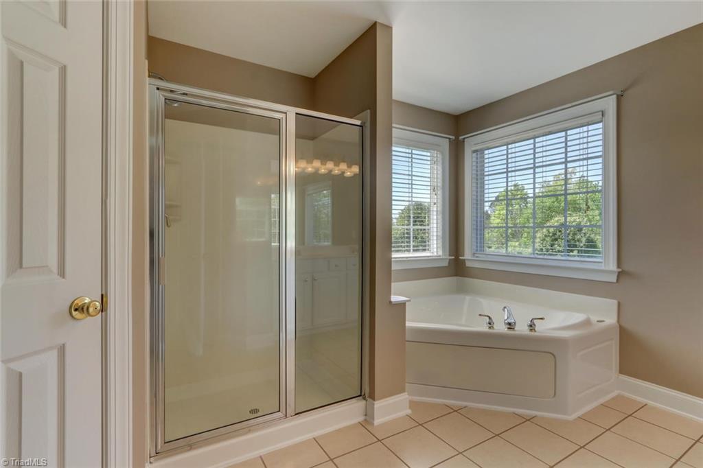 8302 Chartwell Drive Oak Ridge, NC 27310 - Photo 18 of 30 Large spa tub and walk in shower in the master bathroom with two big windows for extra lighting.