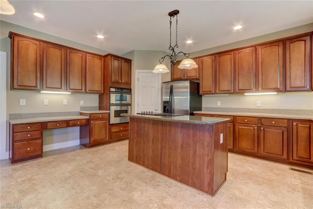 8302 Chartwell Drive Oak Ridge, NC 27310 - Photo 4 of 30 Spacious kitchen with lots of storage in the mahogany cabinets, stove top island and plenty of counter space.