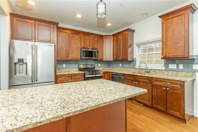 a kitchen with stainless steel appliances granite countertop a stove a sink dishwasher a refrigerator and cabinets with wooden floor