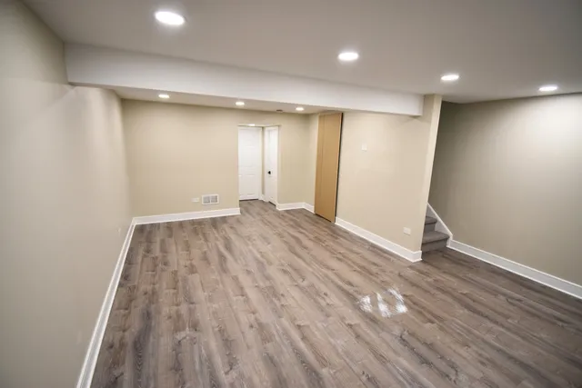 a view of an empty room with wooden floor and closet