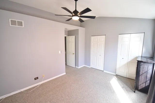 a view of an empty room with a ceiling fan and window