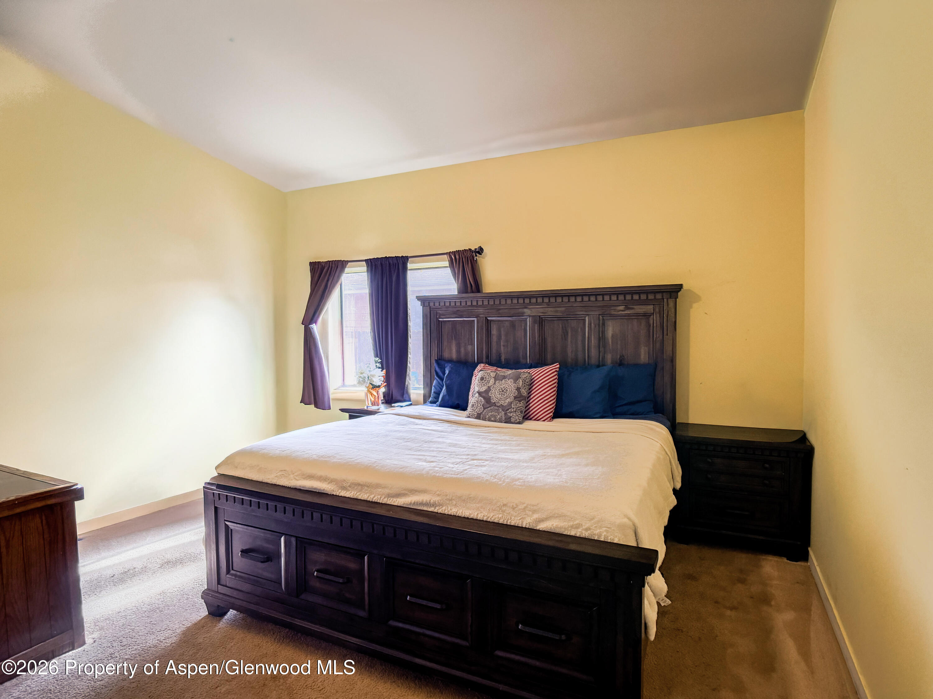 124 Daniel Avenue Rifle, CO 81650 - Photo 9 of 14 a bed sitting in a bedroom next to a window with a chair