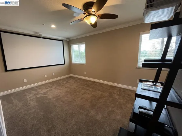 a view of an empty room with window and chandelier fan