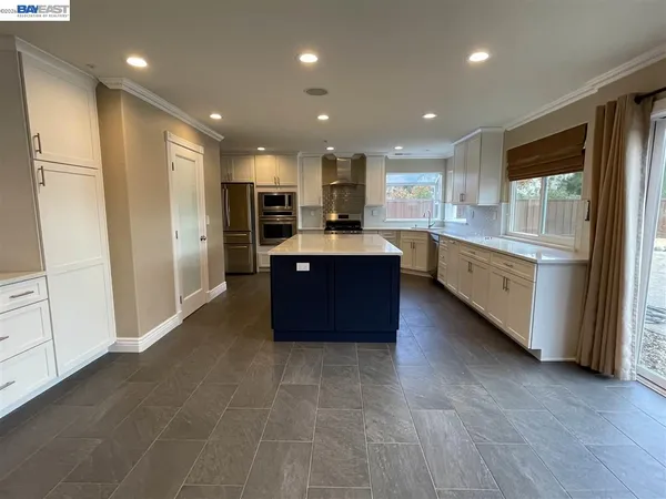 a large kitchen with stainless steel appliances granite countertop a refrigerator and a stove top oven