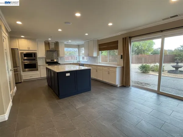 a large kitchen with stainless steel appliances granite countertop a large counter top a refrigerator and a sink