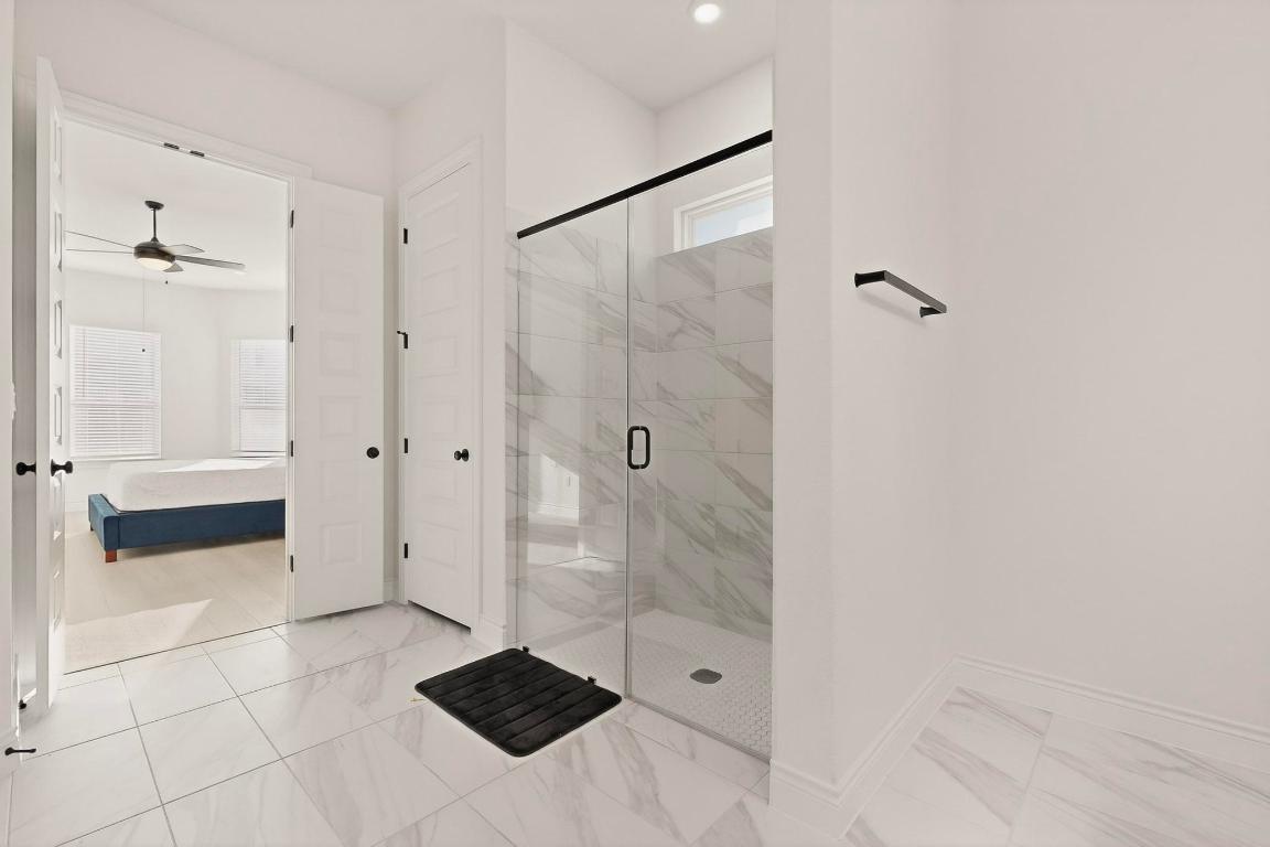 2121 Lolo Lane Leander, TX 78641 - Photo 14 of 26 Bathroom featuring ensuite bath, a marble finish shower, light marble finish flooring, and a ceiling fan