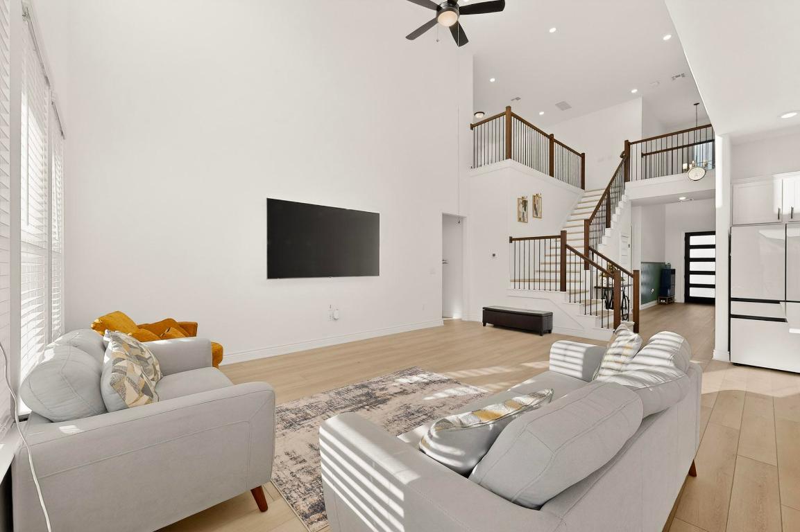 2121 Lolo Lane Leander, TX 78641 - Photo 8 of 26 Living room featuring light wood-style flooring, stairs, a ceiling fan, and a towering ceiling