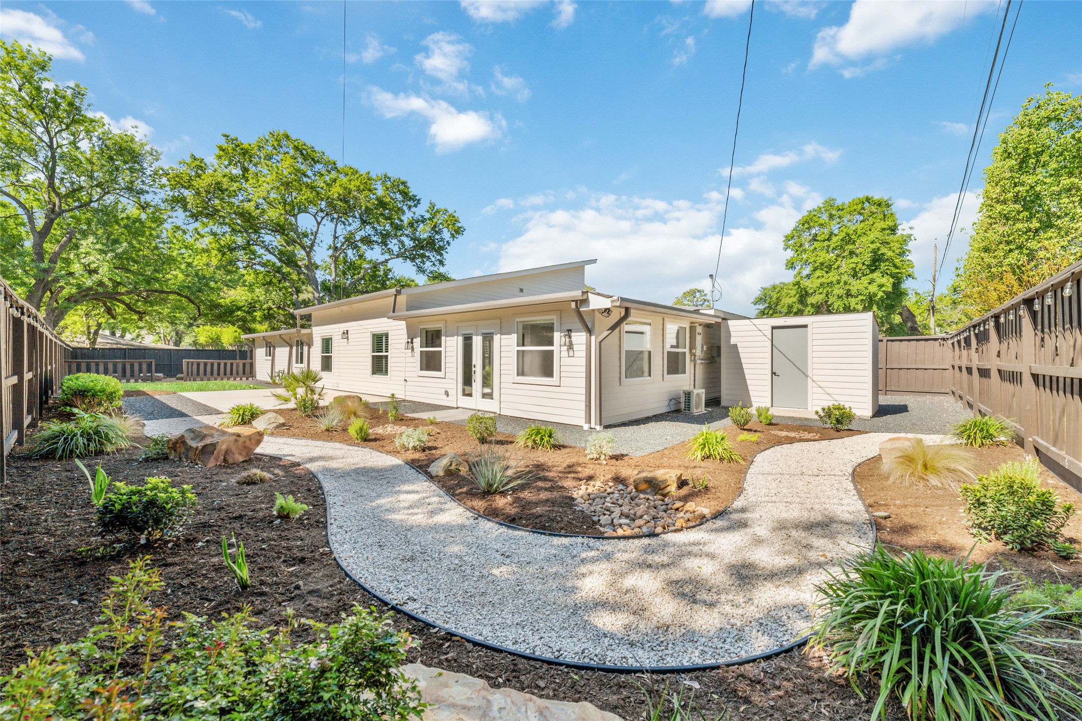 9400 Spring Branch Drive Houston, TX 77080 - Photo 2 of 45 Charming ranch-style home featuring a beautifully landscaped backyard with a winding gravel path, lush greenery, and mature trees, offering a serene outdoor retreat.