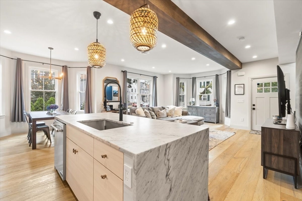 3 Adrian Street, Unit 3 Somerville, MA 02143 - Photo 3 of 31 a large kitchen with granite countertop a large island in the center a sink a window and stainless steel appliances