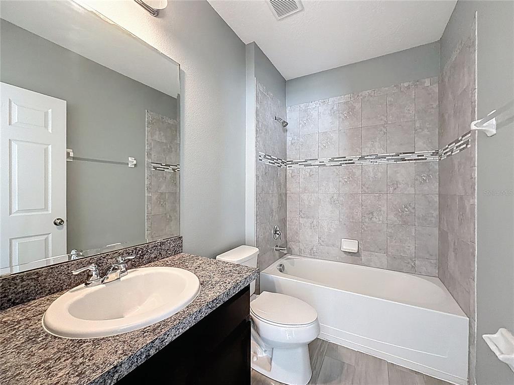 469 Ogelthorpe Drive Davenport, FL 33897 - Photo 9 of 10 a bathroom with a granite countertop sink toilet mirror and bathtub