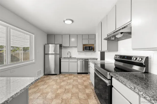 a kitchen with stainless steel appliances granite countertop a sink stove and refrigerator