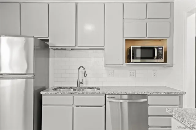 a kitchen with granite countertop a sink cabinets and stainless steel appliances