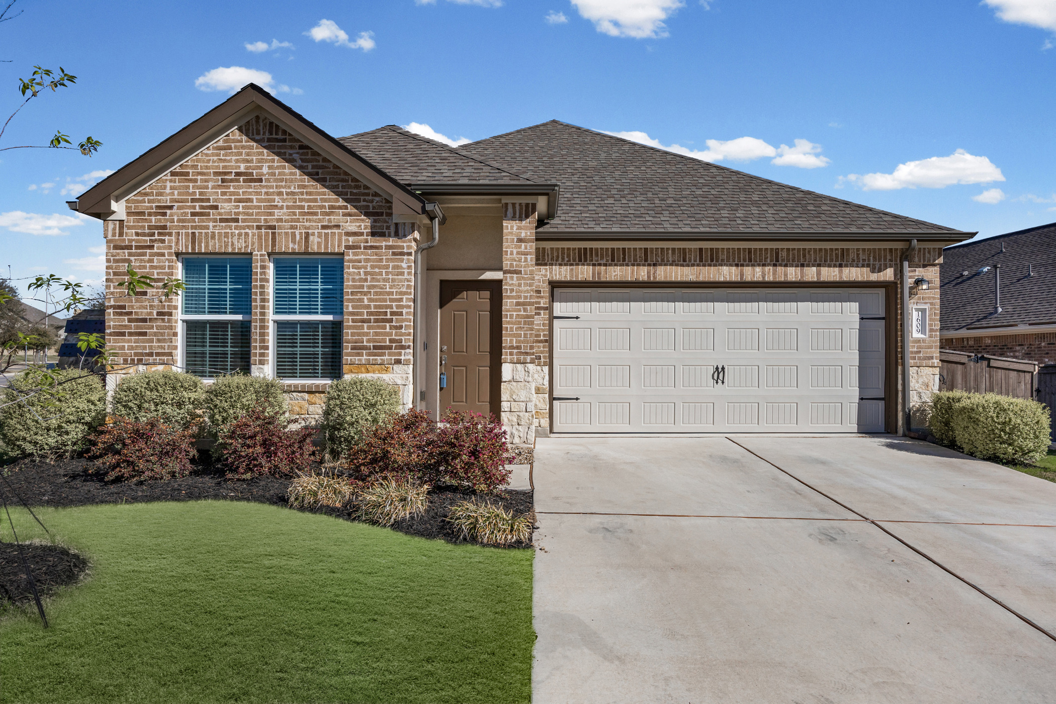 1609 Woolsey Way Leander, TX 78641 - Photo 2 of 29 View of front of house with an attached garage, a front lawn, concrete driveway, brick siding, and a shingled roof