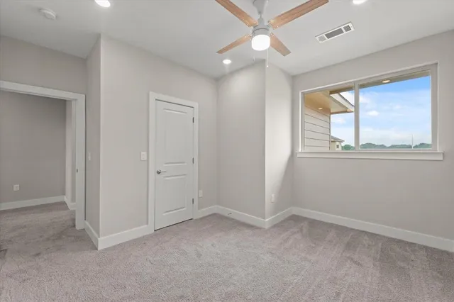an empty room with windows and ceiling fan