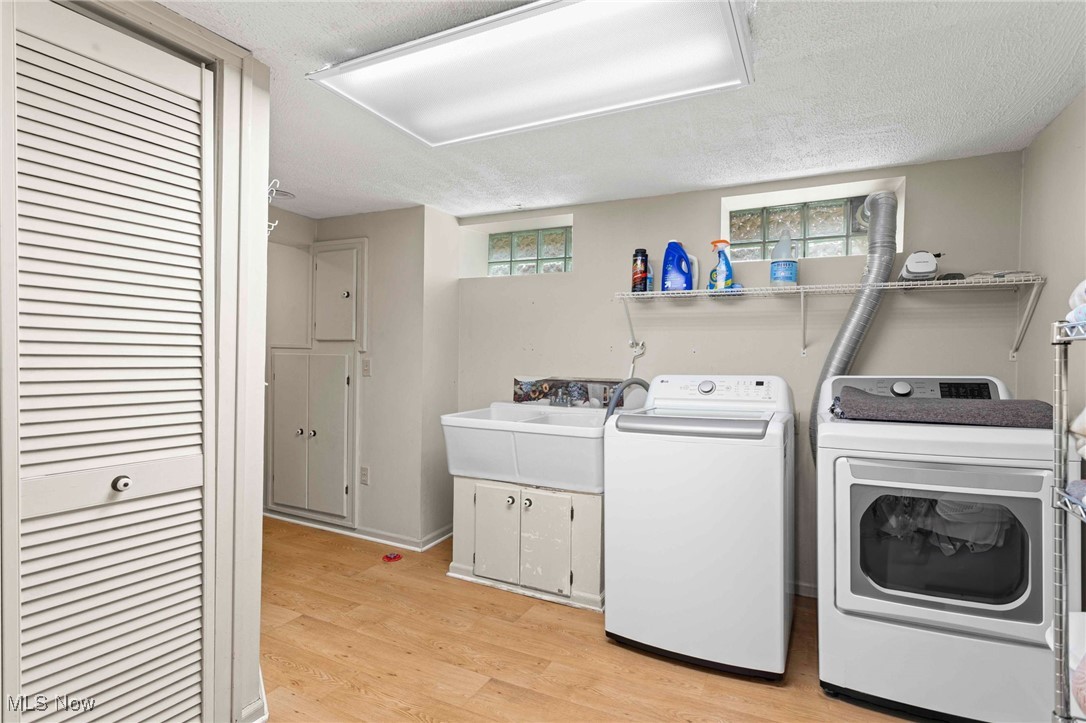 22250 Mastick Road Cleveland, OH 44126 - Photo 32 of 40 Laundry area with washing machine and clothes dryer, a textured ceiling, plenty of natural light, and light wood-style floors