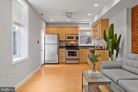 a living room with stainless steel appliances kitchen island furniture and a potted plant