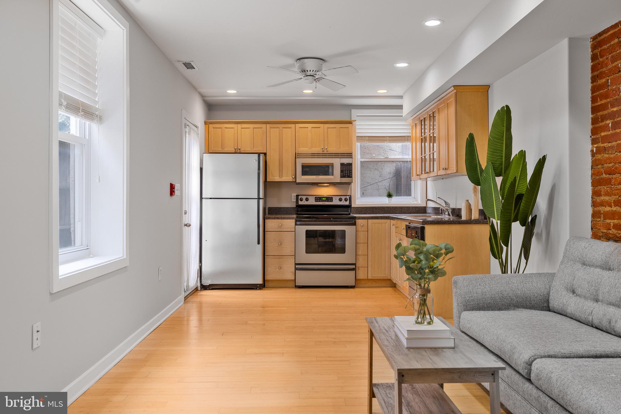 a living room with stainless steel appliances kitchen island furniture and a potted plant