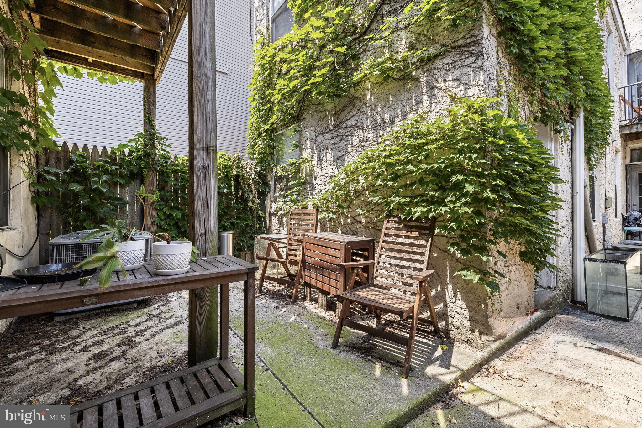 1516 Catharine Street, Unit 2 Philadelphia, PA 19146 - Photo 28 of 31 a patio with table and chairs with potted plants and large trees