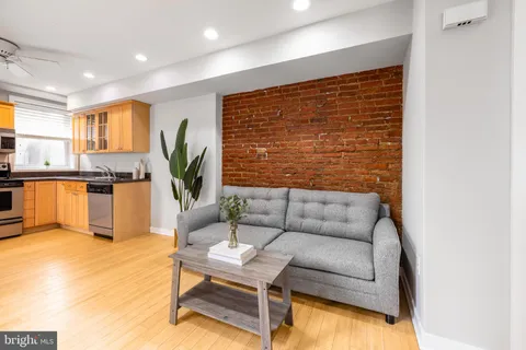a living room with furniture granite countertop kitchen view and a potted plant