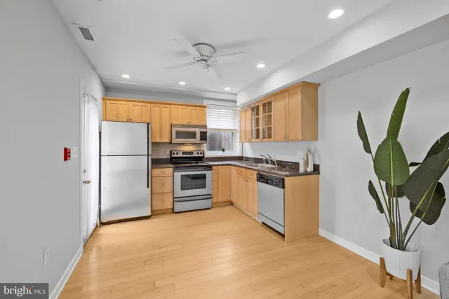 a kitchen with granite countertop a refrigerator a stove a sink a counter space and cabinets