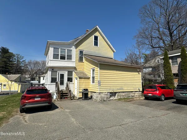 a view of a house with a yard and parking space