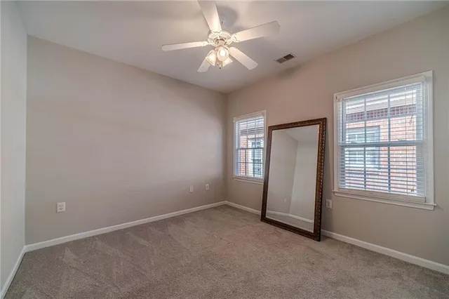 an empty room with chandelier fan and windows