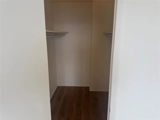 a view of a hallway with wooden floor and a bathroom