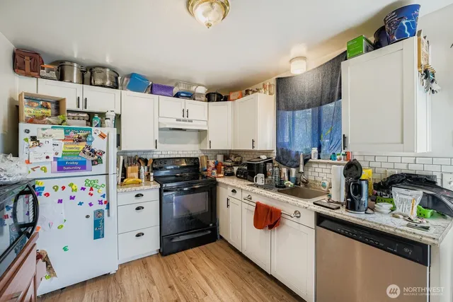 a kitchen with stainless steel appliances granite countertop a white cabinets sink and a refrigerator