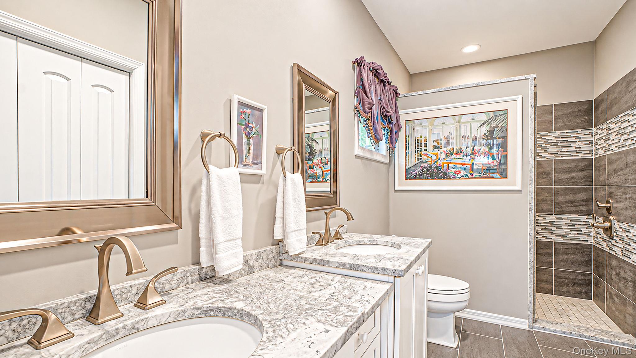 11 Valentine Road Shoreham, NY 11786 - Photo 22 of 40 Spa-inspired master bathroom featuring dual vanities with polished stone countertops, brass fixtures, and an undermount sink design - radiant heated floors